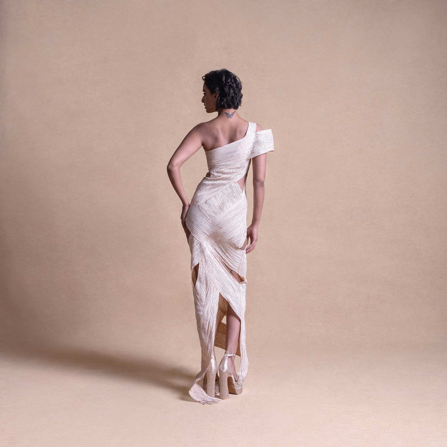 Back view of asymmetrical cream dress with layered wrap panels and cutout details – creative fashion design, fitted dress, resort wear
