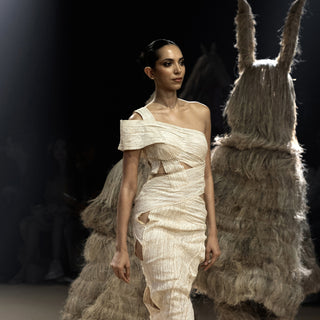 Close-up of model in asymmetrical cream textured dress with cutout detailing – modern resort fashion on runway