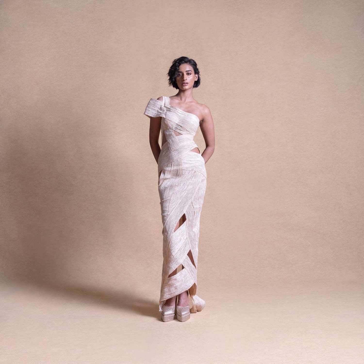 Full-length view of model in asymmetrical cream cutout dress – sculptural wrap detailing, modern resort look