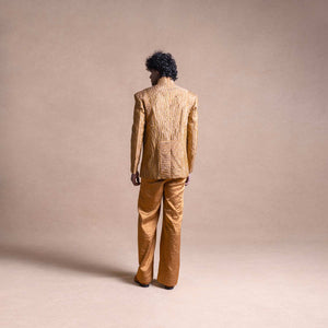 Back view of model wearing a gold textured Bandhgala suit with structured shoulders and wide-leg pants against a neutral beige backdrop - Tuxedo, retro suit, menswear