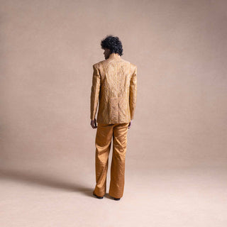 Back view of model wearing a gold textured Bandhgala suit with structured shoulders and wide-leg pants against a neutral beige backdrop - Tuxedo, retro suit, menswear
