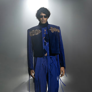 male model wearing a blue outfit with intricate designs on a gray background