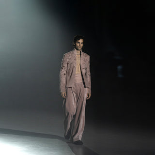 High-fashion men’s dusty pink ensemble with detailed jacket and relaxed fit pants on runway catwalk