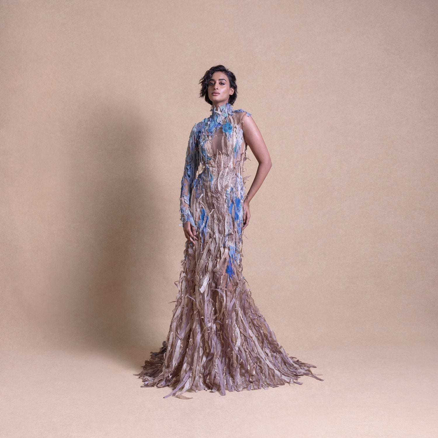 Model in eco-luxury gown inspired by crop fields with blue floral accents on neutral studio backdrop - eco-luxury fashion, reception gown