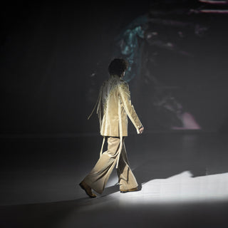 Person walking on a dark stage with a projected image in the background