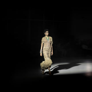 Women’s gold embellished cape with textured ruffled skirt and fitted silhouette showcased on runway