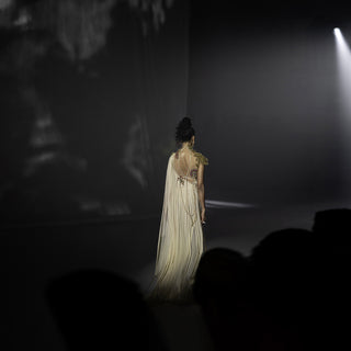 Model walking on a runway in a dark setting with spotlight