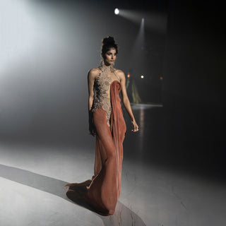 Women’s rust draped evening dress with embellished high-neck bodice and flowing silhouette on runway