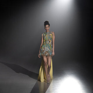 Women’s embellished short dress with multicolor embroidery and yellow sheer train walking runway under spotlight