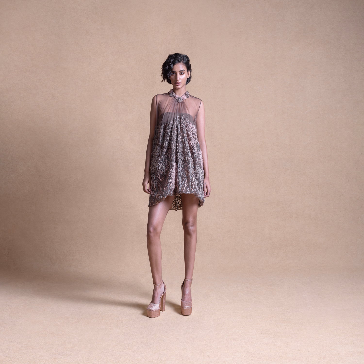 Front view of a model wearing a sleeveless, sheer balloon mini dress with a softly pleated silhouette in neutral tones - artistic high fashion outfit, youngester dress, luxury womenswear