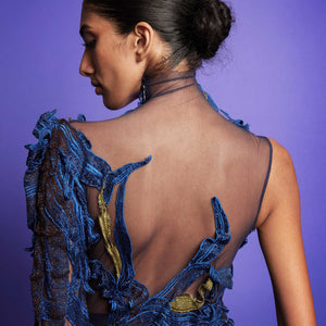 Close-up of the back of a model wearing an asymmetrical couture gown with sheer mesh and blue and gold embroidered embellishments -  close-up fashion, embroidery detail, red carpet couture gown, cocktail gown