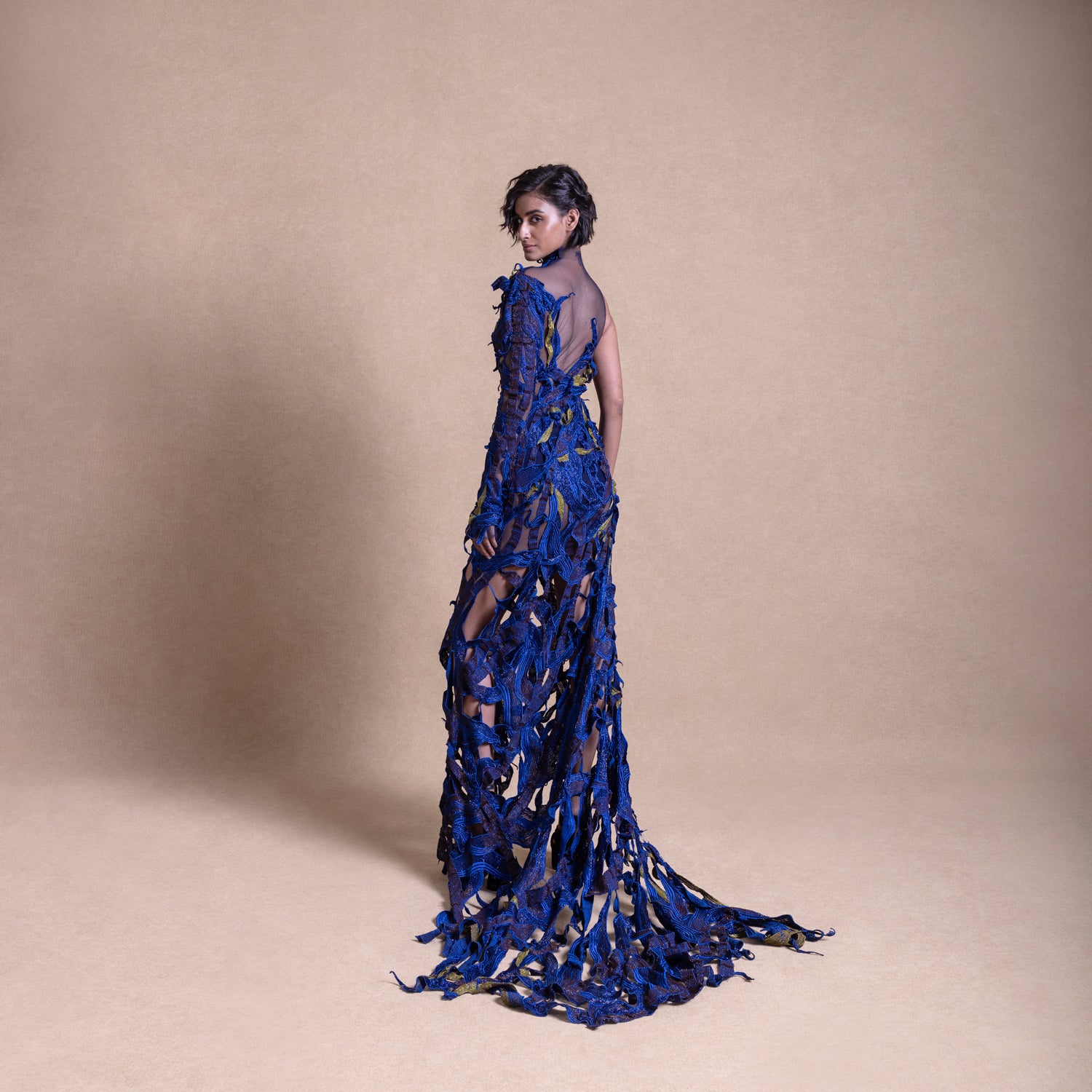 Model posing with her back, electric blue mesh gown, one-sleeve design - red carpet couture gown, cocktail gown, asymmetric dress