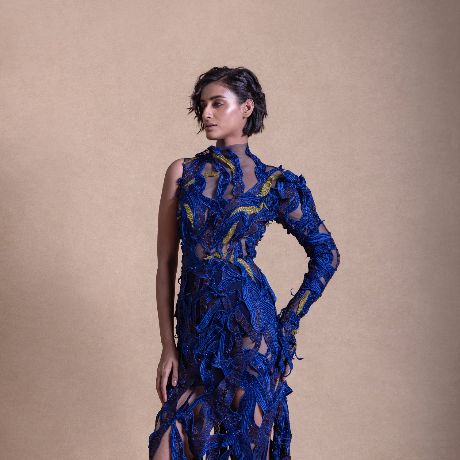 Close-up of a model in a bold electric blue gown with intricate appliqué and sheer mesh fabric, featuring a one-sleeve design - fashion portrait, red carpet couture gown, cocktail gown, electric blue dress