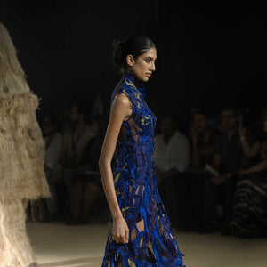 Side profile of model in bold electric blue asymmetrical gown with textured embroidery and sheer cutouts - red carpet couture gown, cocktail gown