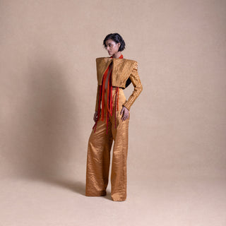 Model in Structured designer jacket with flared pants angular shoulders and cascading red beaded fringe, posing against a neutral beige background - high fashion ensemble, powershoulder jacket, metallic.