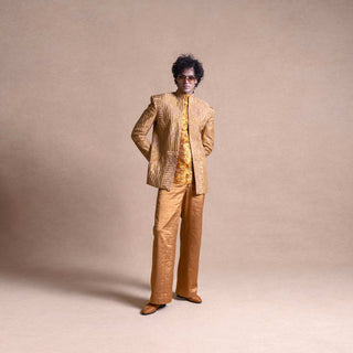 Model in gold Bandhgala suit with metallic embroidery and textured shirt, standing against beige studio background - Tuxedo, retro suit, menswear