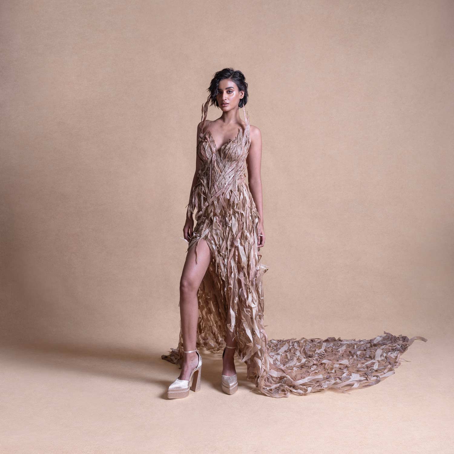 Full-length studio shot of model in nude corset gown with shredded fringe train - couture runway dress, eveningwear fashion