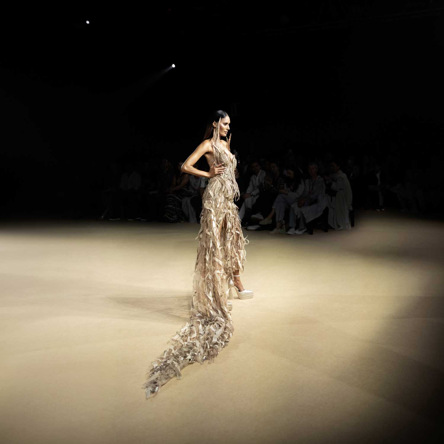 Model in corset gown with long feathered trail on runway - futuristic couture ensemble. redcarpet cocktail gown,  feather trail dress, runway fashion