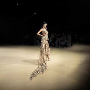 Model in corset gown with long feathered trail on runway - futuristic couture ensemble. redcarpet cocktail gown,  feather trail dress, runway fashion
