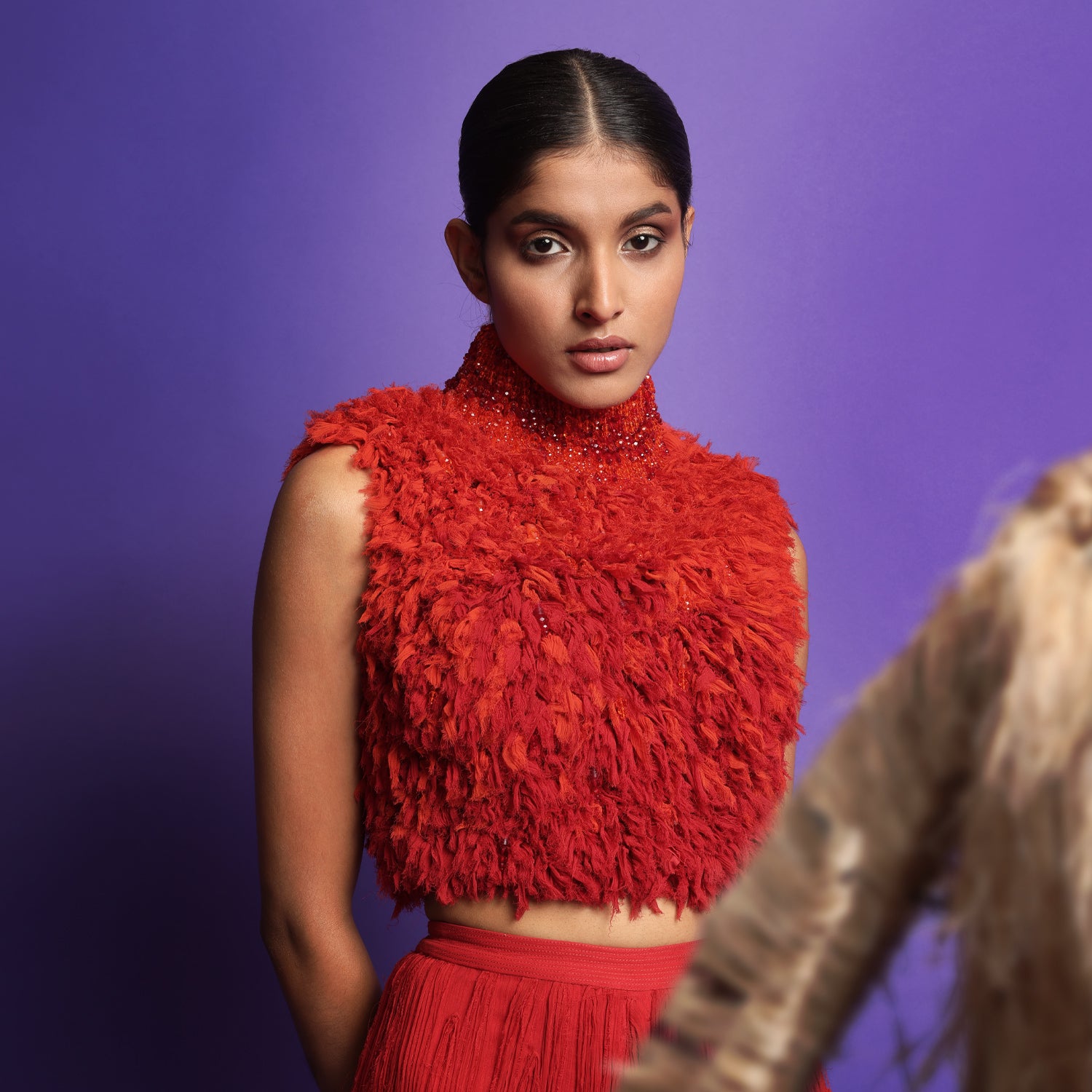 Close-up of model wearing a vibrant red textured sleeveless crop top with high neckline, paired with pleated red flared pants - lightweight modern silhouette, jumpsuit