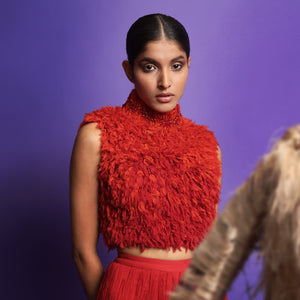 Close-up of model wearing a vibrant red textured sleeveless crop top with high neckline, paired with pleated red flared pants - lightweight modern silhouette, jumpsuit