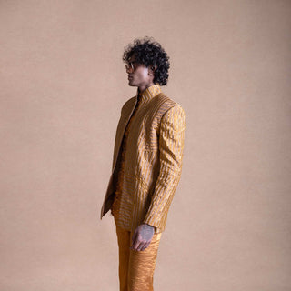 Model in profile wearing gold textured Bandhgala suit with matching trousers, against a neutral beige background - Tuxedo, retro suit, menswear 