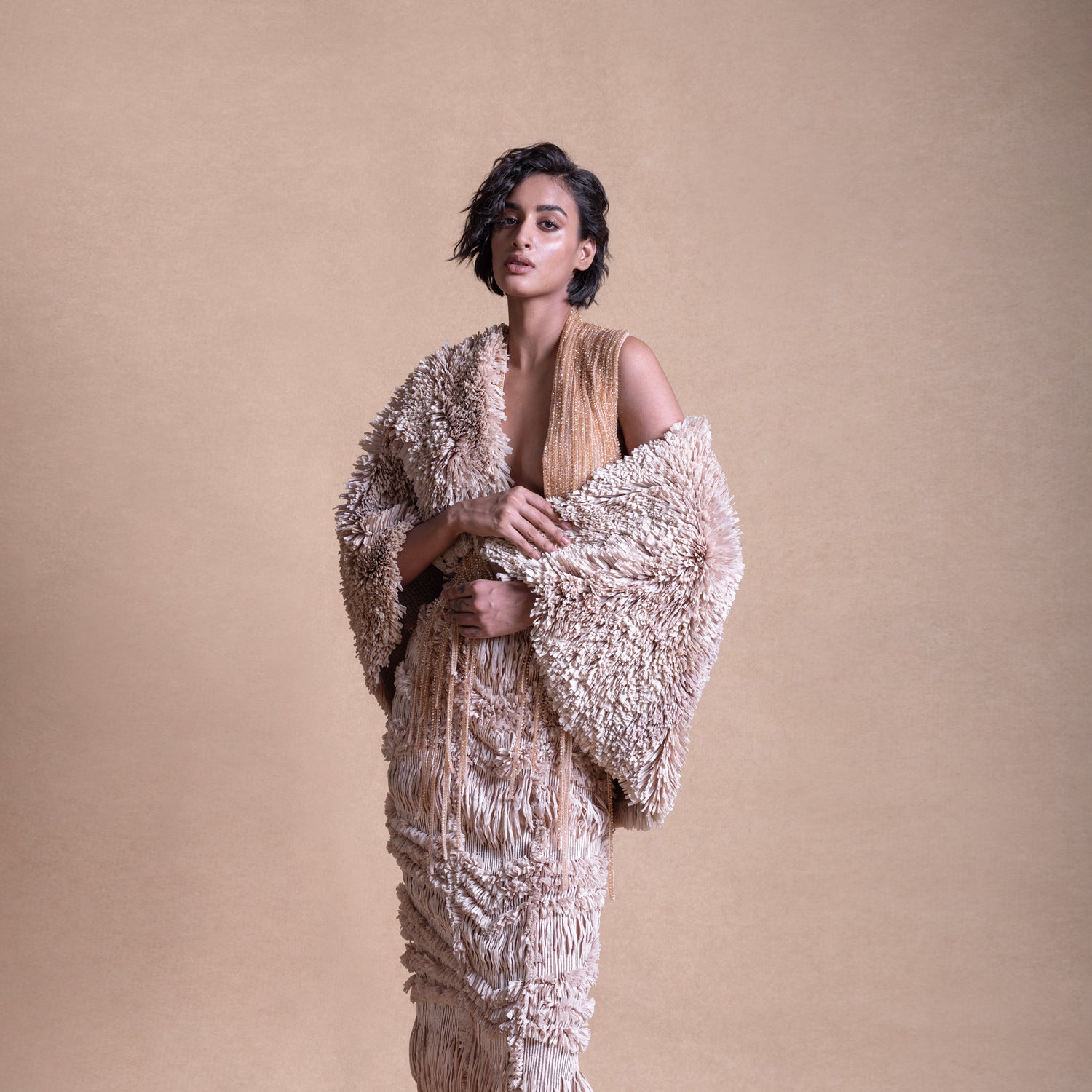 Backless dress with textured cape and intricate string details – contemporary fashion portrait, avant-garde style