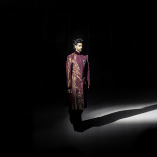 Man wearing a patterned suit standing in a dark room with a spotlight