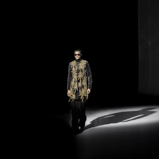 Men’s embellished black velvet sherwani jacket with ornate gold detailing showcased on runway