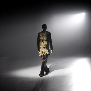 Men’s black velvet embroidered short sherwani with statement gold motifs under dramatic runway lighting