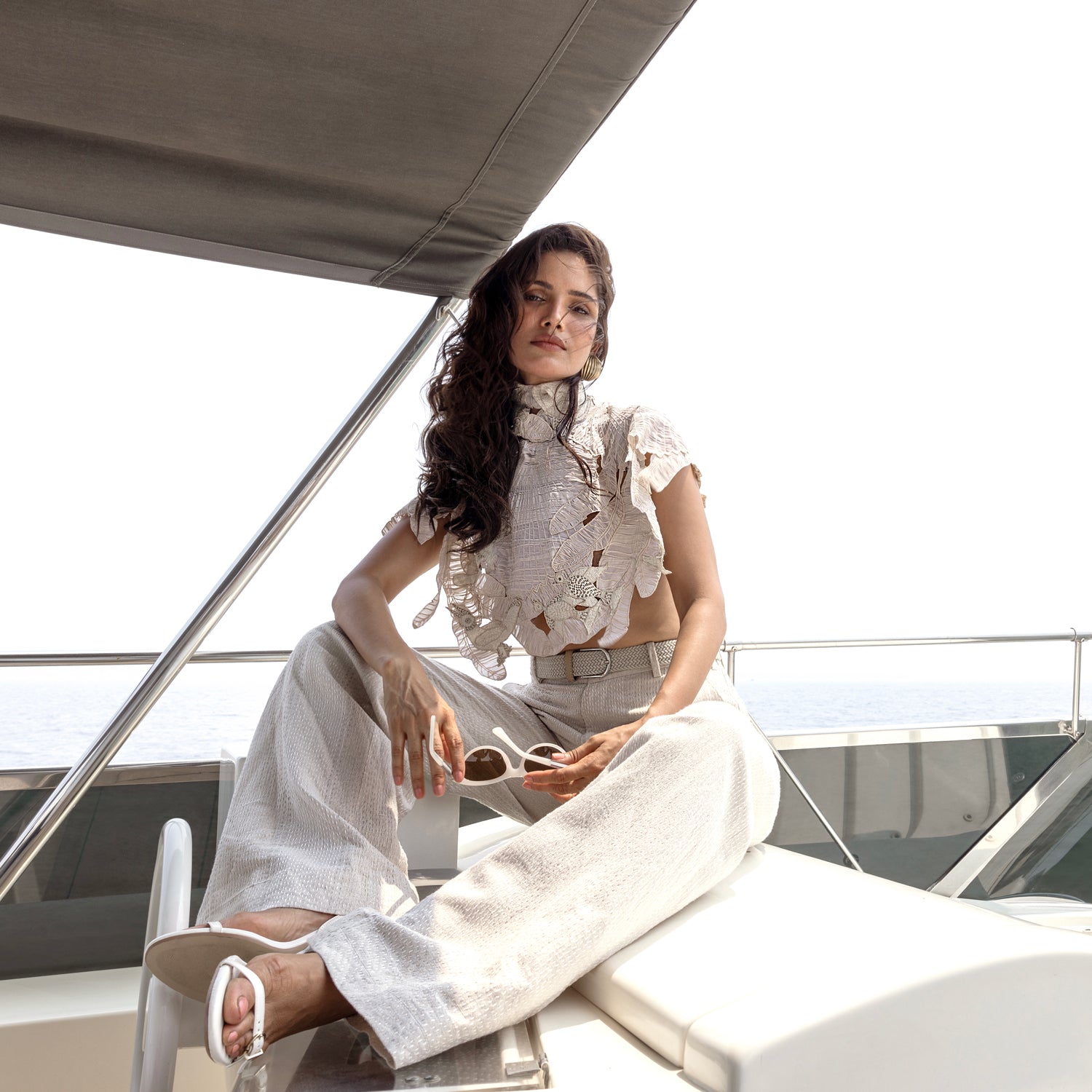 Women's lace-detailed ivory cape with soft ruffles and high neck, paired with flared trousers – romantic outfit for seaside events