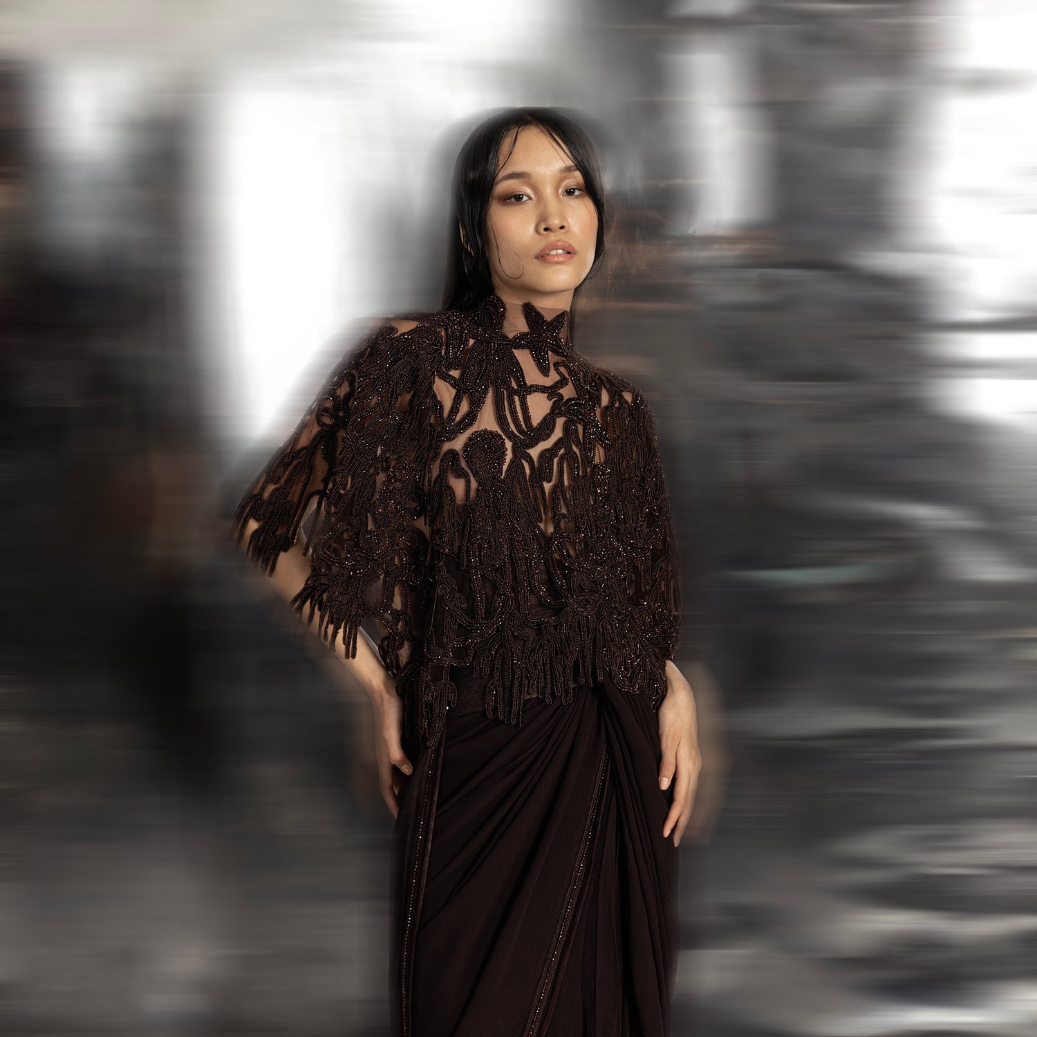 Women's sheer black high-neck cape with reef-inspired 3D embroidery over draped chiffon saree – modern couture layering