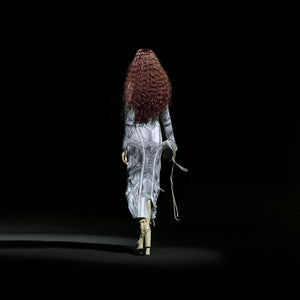 Back view of women's full sleeve sculpted dress with textured pattern and tassel clutch – modern party runway look