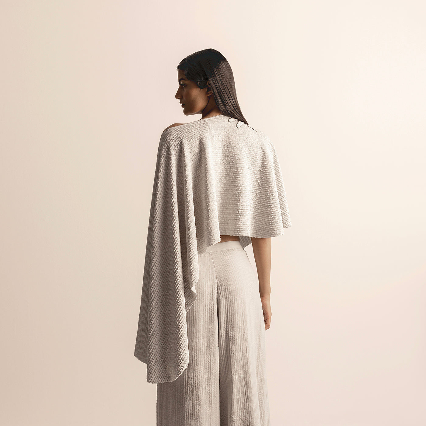 back close-up of Women's taupe knit cape crop top with asymmetric back drape and high-waisted quilted pants - creative Indo-western ensemble