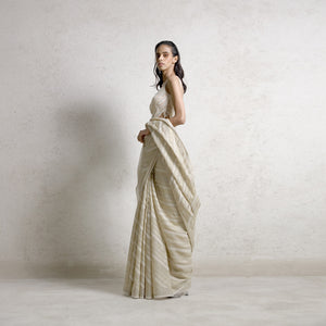 Handwoven tusser silk saree with gold zari pattern embellished with fine pearl and katdana detailing teamed up with draped pearl string blouse. the look is perfect for traditional and modern-day styling. There is a delicate and intense play of pearl strings of varied sizes. #Abhishekstudio #abhisheksharma  #fashiondesignerabhisheksharma #designerware #ambawattaone #lakmefashionweek  #weddingware #bridal #modrenbride #chikankari