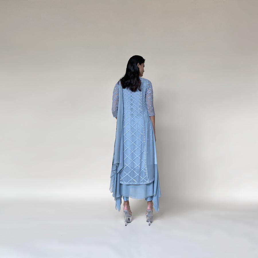 Chiffon Kalidas kurta with fine Resham shadow work and sequin embroidery. The kurta set has layered look and comes with a draped shaped stole, fitted pants and separate flared lining. The look is perfect for a refreshing and relaxed day. The look is perfect when you want to carry the grace and elegance with understated style. 