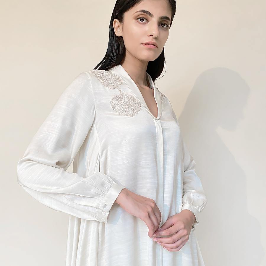 Satin circular-cut top with shawl collar and placement fine Resham and pearl embroidery teamed up draped pants. The look has an elegant and graceful vibe with a hint of style. It's a perfect pick for the day when you want to slay in style and comfort.   styling: Nude heel will complete the look along with diamond studs and ring. abhishekstudio, Abhishek Sharma 