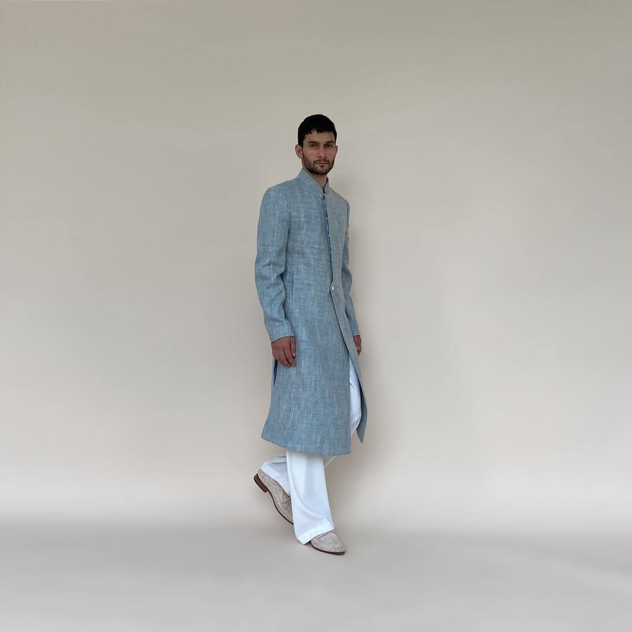 Shaped mandarin collar sherwani with single button front overlap closure. Heavy weight cotton khadi sherwani features high slits and slightly layered panels for that extra ease while sitting and or on the go. Sherwani is embellished with sequin and pearl lotus appliqué on the sleeve.  abhisheksharma , abhishekstudio
