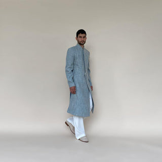 Shaped mandarin collar sherwani with single button front overlap closure. Heavy weight cotton khadi sherwani features high slits and slightly layered panels for that extra ease while sitting and or on the go. Sherwani is embellished with sequin and pearl lotus appliqué on the sleeve.  abhisheksharma , abhishekstudio