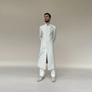 Shaped mandarin collar sherwani with mother of pearl buttons. Heavy weight handloom matka silk sherwani features high slits and slightly flared double princess panels for that extra ease while sitting and or on the go. Sherwani is embellished with palm leaf bugle bead embroidery in pastel colours.  abhisheksharma , abhishekstudio 