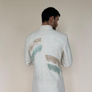 Shaped mandarin collar sherwani with mother of pearl buttons. Heavy weight handloom matka silk sherwani features high slits and slightly flared double princess panels for that extra ease while sitting and or on the go. Sherwani is embellished with palm leaf bugle bead embroidery in pastel colours.  abhisheksharma , abhishekstudio 