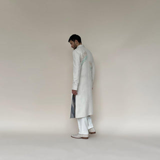 Shaped mandarin collar sherwani with mother of pearl buttons. Heavy weight handloom matka silk sherwani features high slits and slightly flared double princess panels for that extra ease while sitting and or on the go. Sherwani is embellished with palm leaf bugle bead embroidery in pastel colours.  abhisheksharma , abhishekstudio 