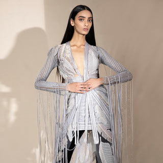 Close-up of women’s floor-length embroidered jacket with leaf motifs and beaded fringe sleeves over mini skirt – bold cocktail co-ord for parties