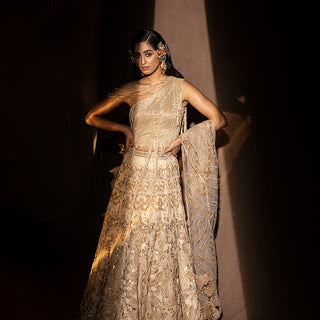 front view of Women's gold embroidered lehenga with one-shoulder drip-detail blouse and sheer dupatta – designer bridal set for sangeet or cocktail night