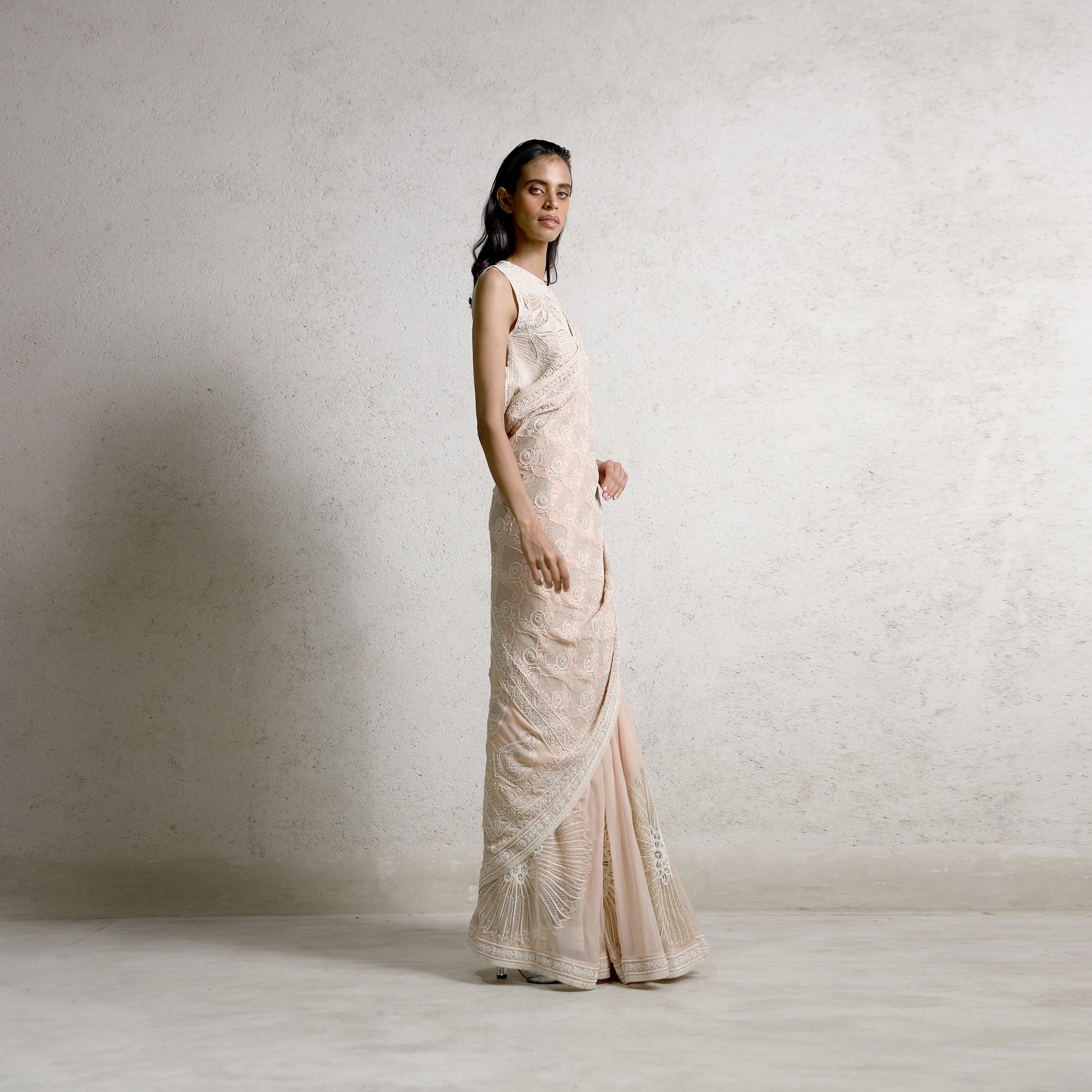 full-length profile shot Women's blush chikankari saree with flared embroidered hem and sleeveless heritage blouse – artisanal pre-draped silhouette for festive elegance