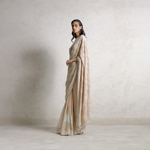 full length side shot of Women's blush net chikankari saree with floral jaali embroidery and flared pleated hem – heritage-inspired silhouette for cultural festivities